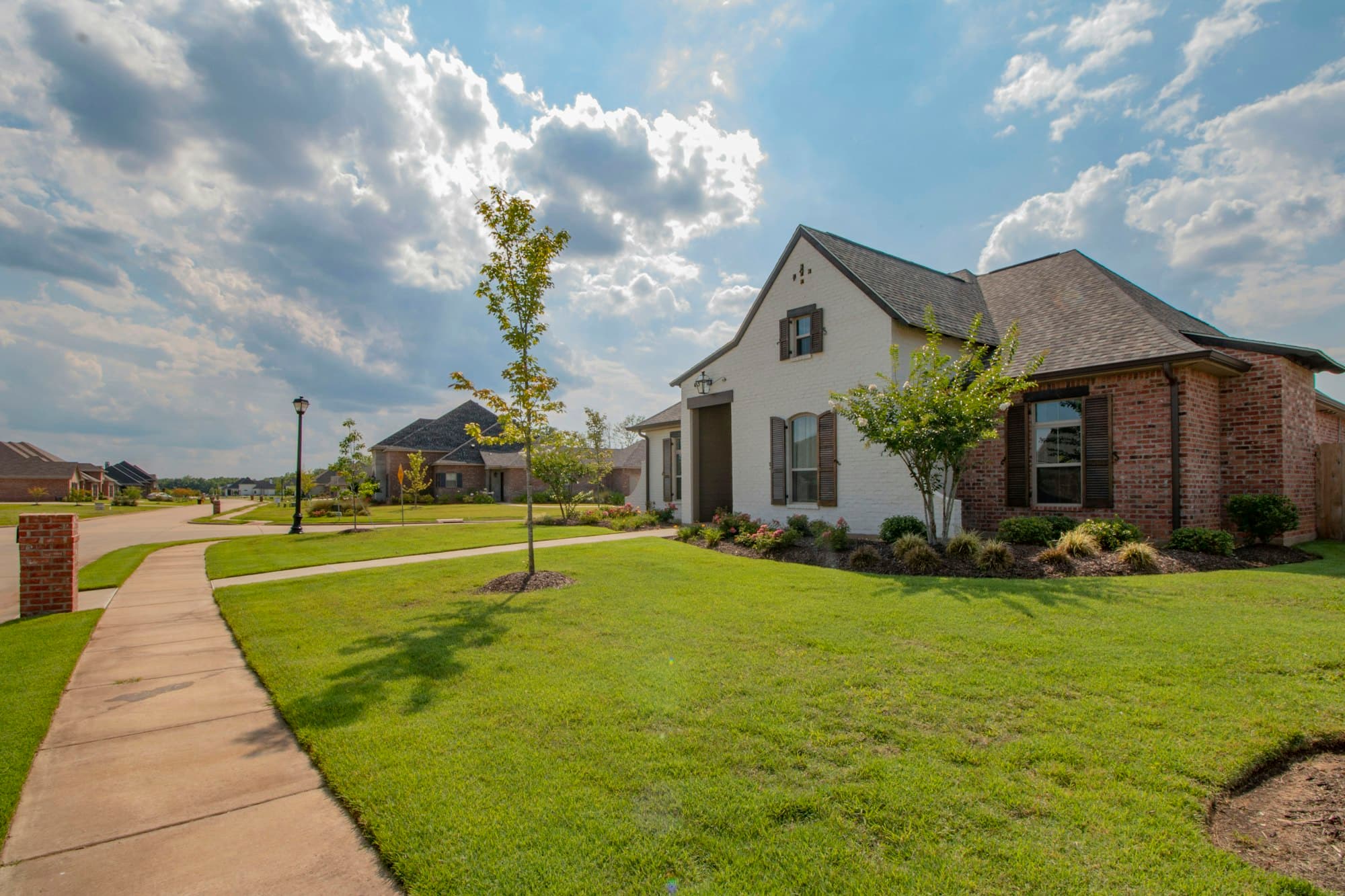 A brick home with a wide front lawn on a quiet residential street